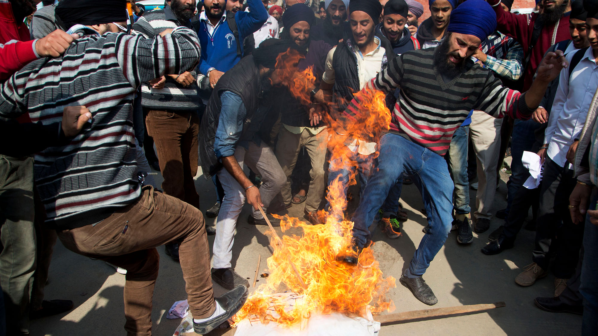 Kashmiri Sikhs kick a burning effigy of Gurmeet Ram Rahim Singh, chief of  Dera Sacha Sauda. (Photo: AP)