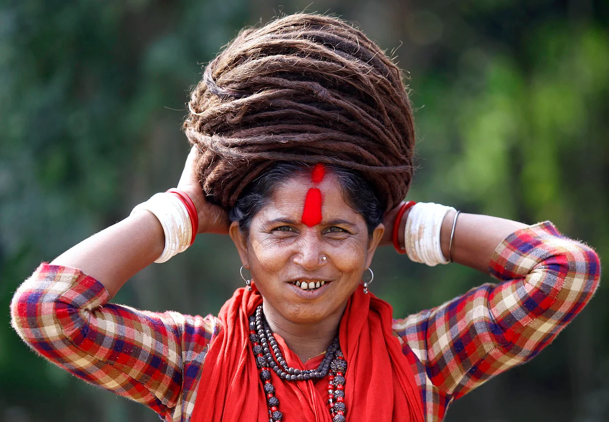 A Hindu ascetic woman smiles as she adjusts her hair after taking a dip in the Ganga river (Photo: Reuters)