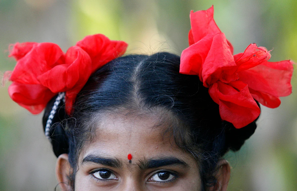 Kamala, an Indian girl wears red ribbons in her hair. (Photo: Reuters)