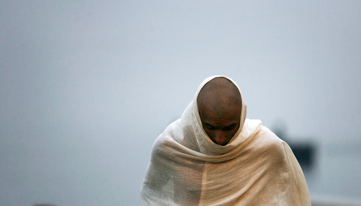 A man is draped in a traditional white robe in front of a pyre of a family member at a cremation ground on the banks of river Ganges in Varanasi. (Photo: Reuters) 