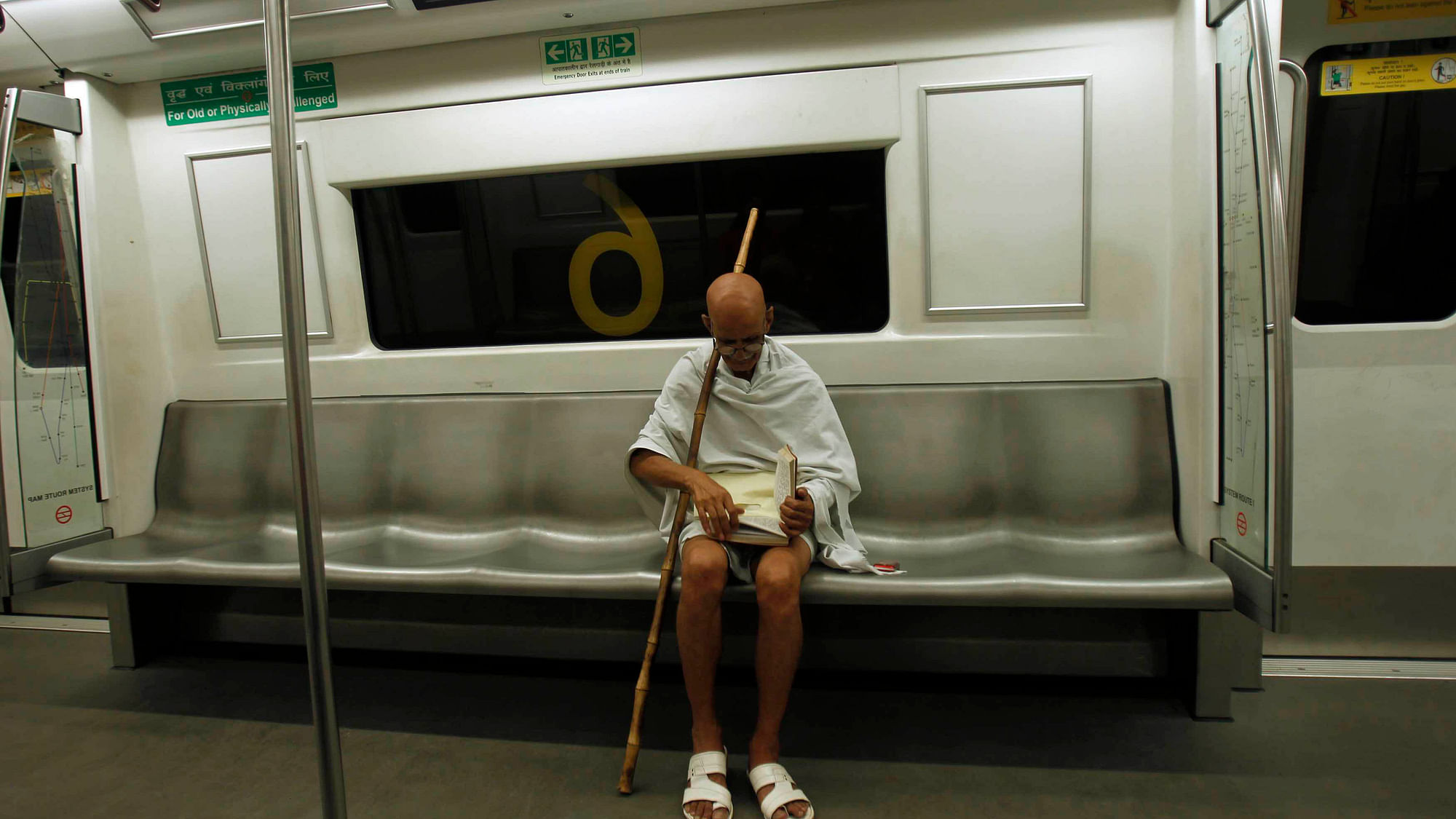 Mahesh Chaturvedi, who dresses up like Mahatma Gandhi, reads a copy of the Bhagavad-Gita, on a metro train in New Delhi (Photo: Reuters)