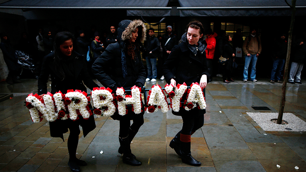 Women carry a floral tribute at an event to mark Nirbhaya’s first anniversary outside the Indian High Commission in Central London, December 16, 2013. (Photo: Reuters)
