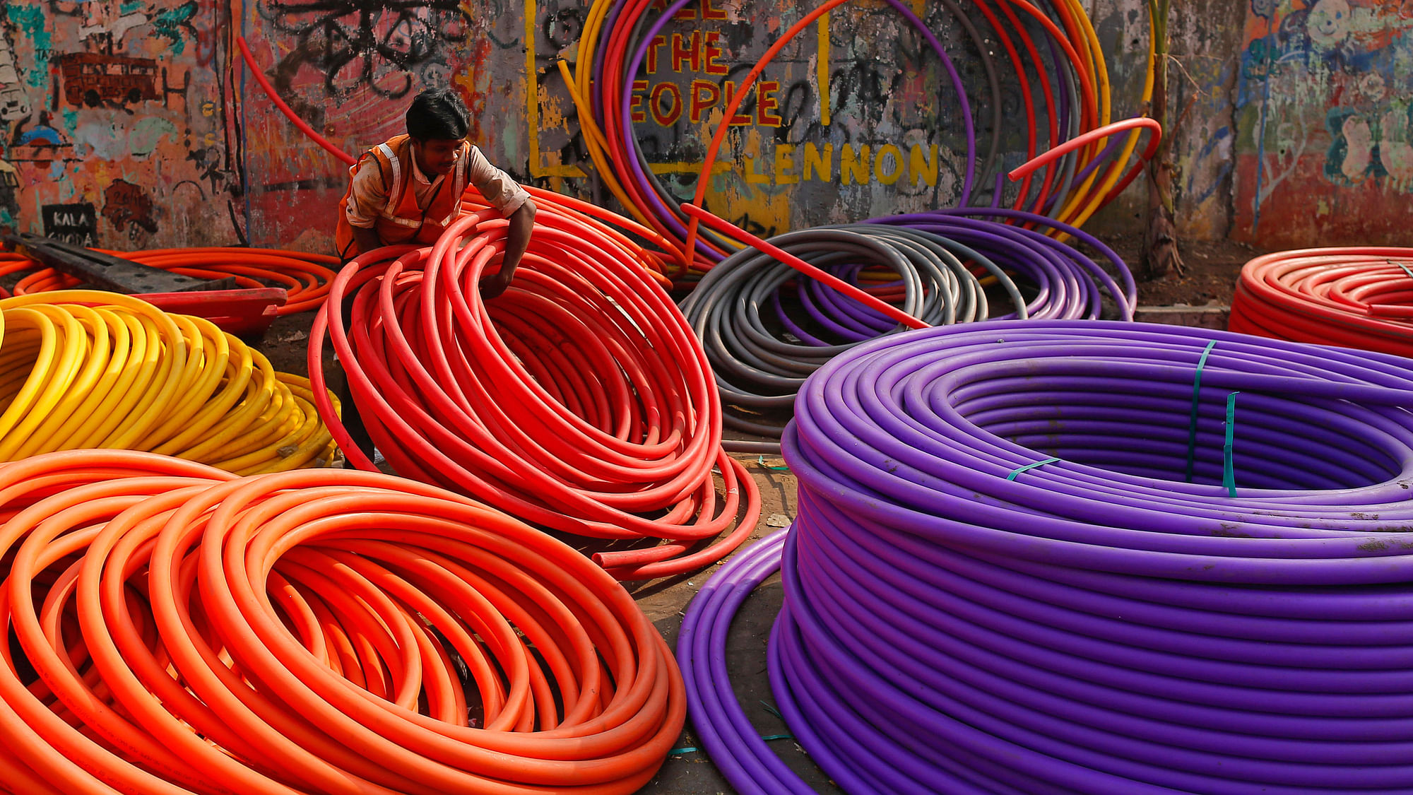 A labourer works amid rolls of underground telephone cable pipes on the side of a road in Mumbai. (Photo: Reuters)