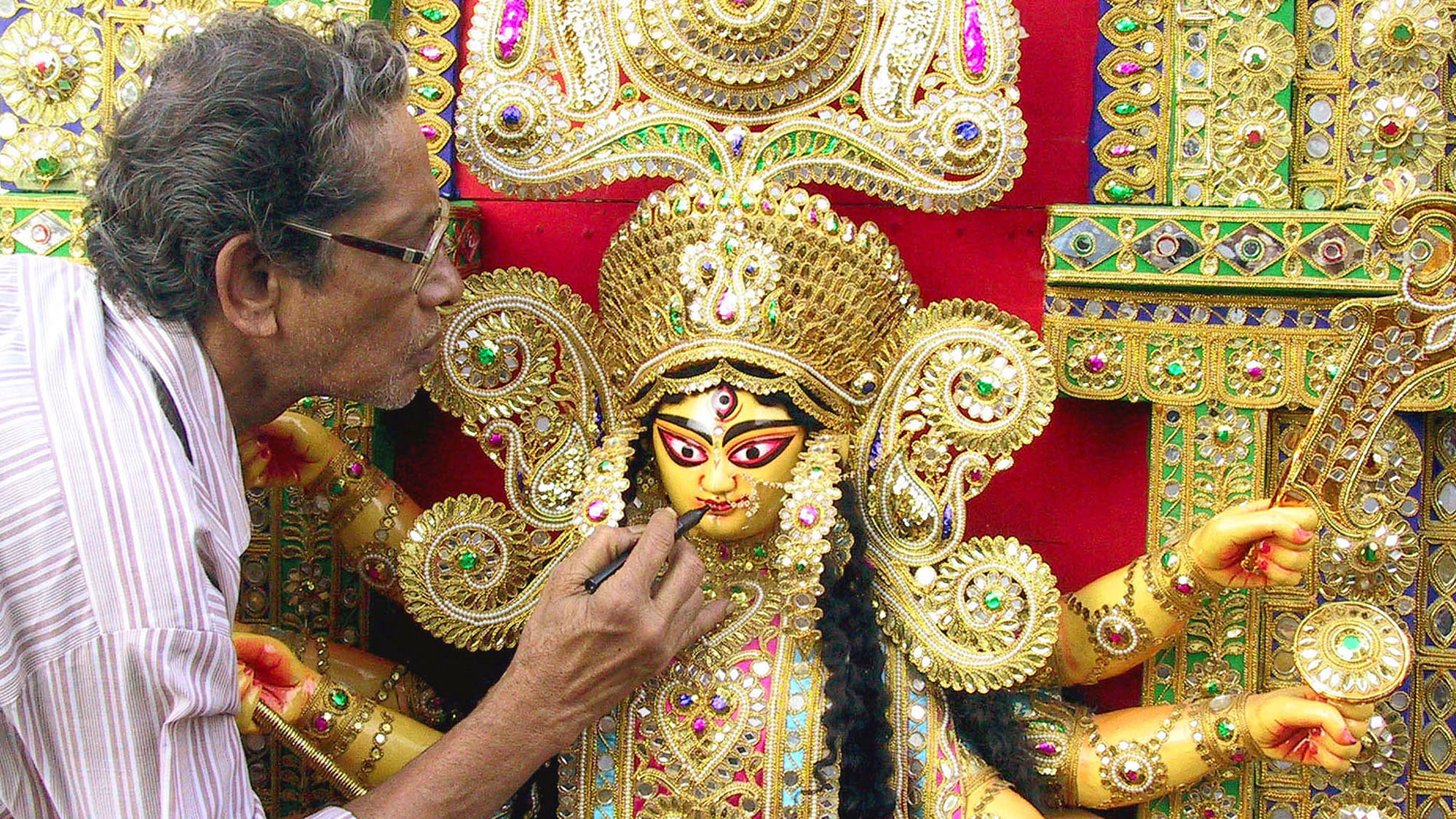 Indian sculptor Amar Nath Ghosh applies the finishing touches to an idol of the Hindu goddess Durga in Calcutta, October 3, 2002. (Photo: Reuters)