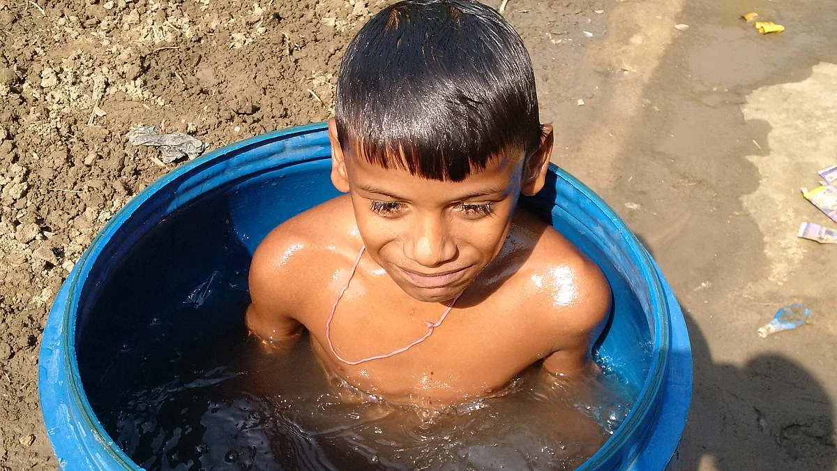 Ram Kumar’s son taking a dip in a plastic barrel at their modest brick-built house in Mathura hamlet in Checher village near Bidupur in Vaishali district. (Photo: <b>The Quint</b>) 