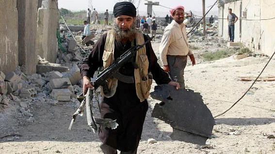 An Islamic State militant carries a piece of wreckage from a Syrian war plane after it crashed in Raqqa, in north-east Syria. (Photo: Reuters)