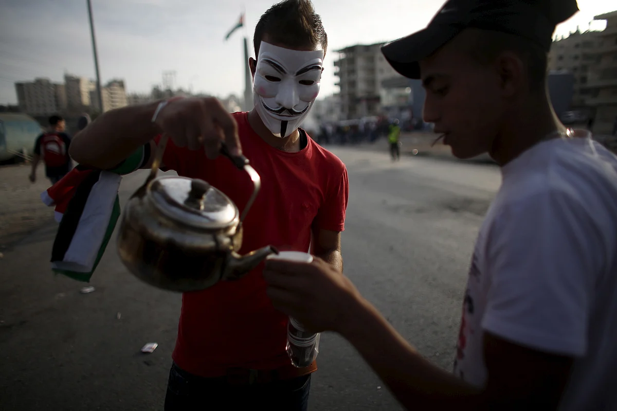 A masked protester pours tea for his comrade. (Photo: Reuters)