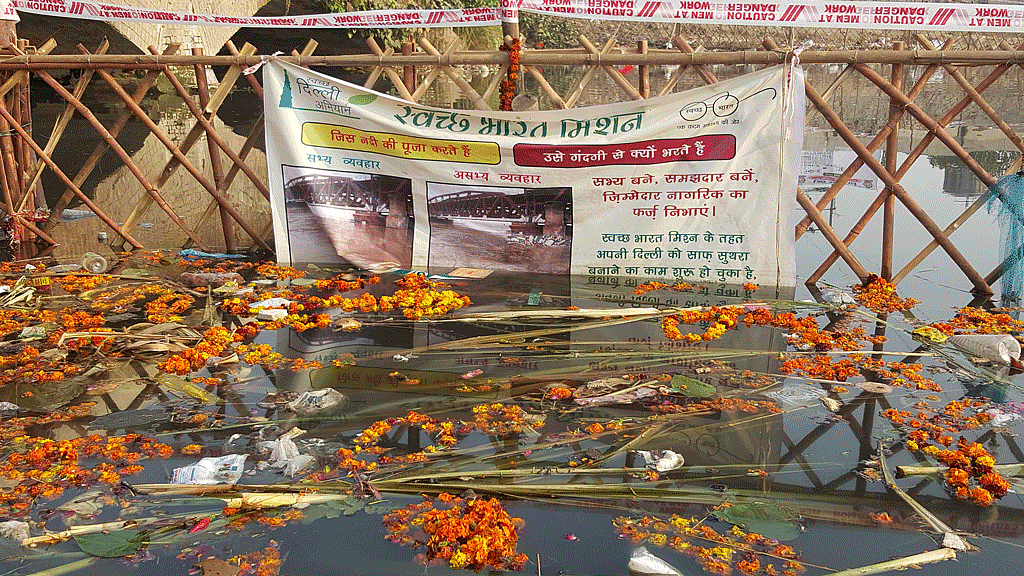 A Swachh Bharat Abhiyan banner was seen hanging on a fence in the canal amidst the waste. (Photo: <b>The Quint</b>)