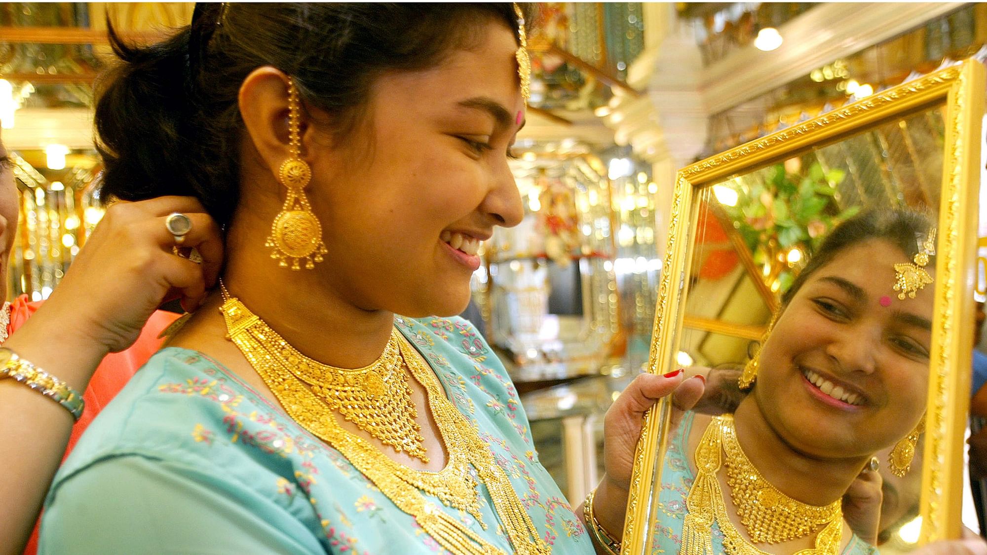 A woman tries gold ornaments on the occasion of the Hindu festival of Dhanteras in Kolkata.&nbsp;