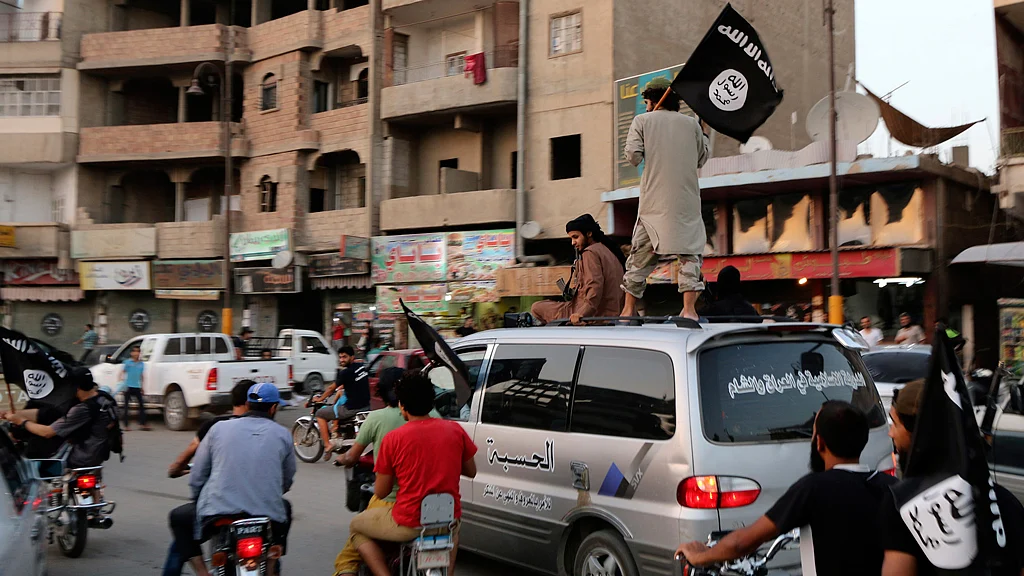 Members loyal to the ISIS in Iraq and the Levant (ISIS) wave ISIS flags as they drive around Raqqa, Syria. 