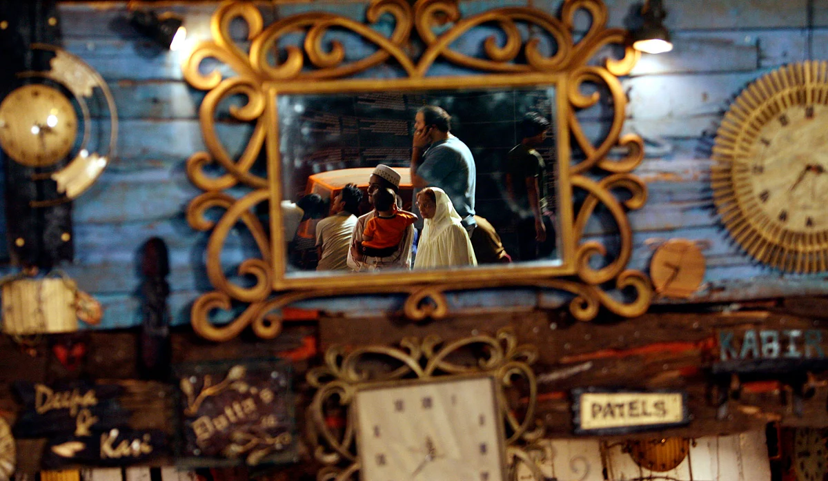 Visitors are reflected in a mirror at a curio shop at the Kala Ghoda arts festival in Mumbai February 13, 2009. (Photo: Reuters)