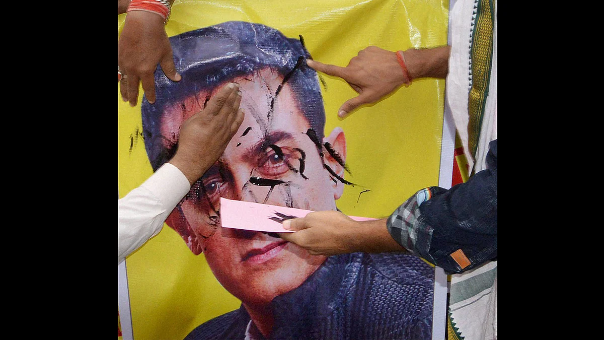 BJP workers putting black ink on a poster of Actor Amir khan during a protest against his statement. (Photo: PTI)