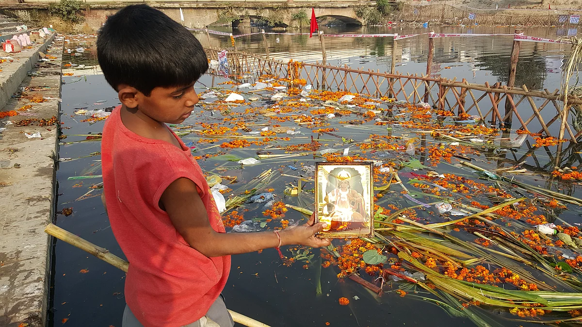 A boy shows a picture frame of Lord Hanuman that he picked from the waters. (Photo: <b>The Quint</b>)