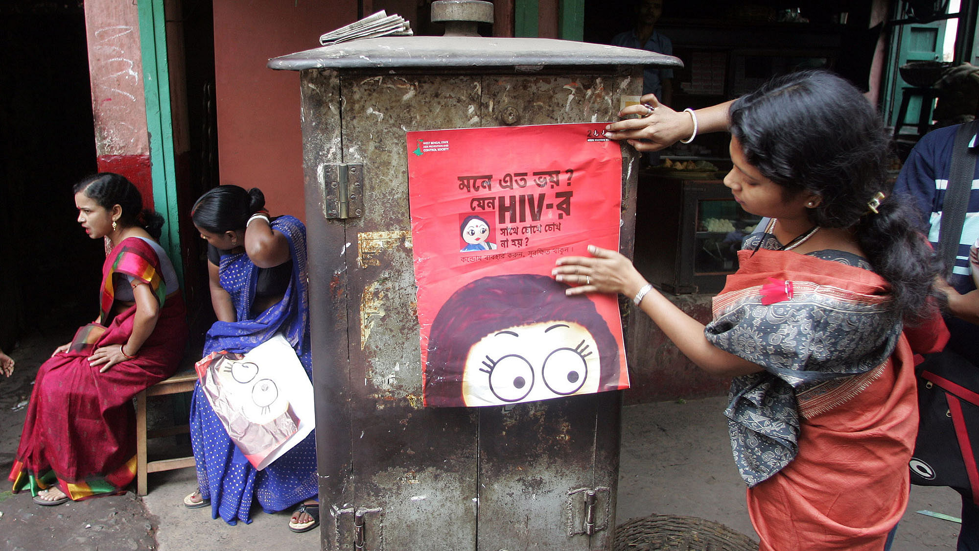 An activist puts up a poster during an AIDS awareness
drive in Sonagachi. (Photo: Reuters)