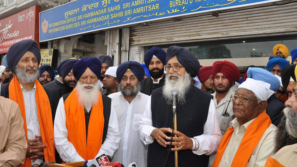 A file picture of Punjab Chief Minister Parkash Singh Badal (speaking into a public address system) and Deputy Chief Minister Sukhbir Singh Badal (to Badal senior’s right). (Photo courtesy: <a href="https://www.facebook.com/AkaliDalBadal/photos/pb.268373753220345.-2207520000.1448356320./326160747441645/?type=3&amp;theater">Facebook</a>)