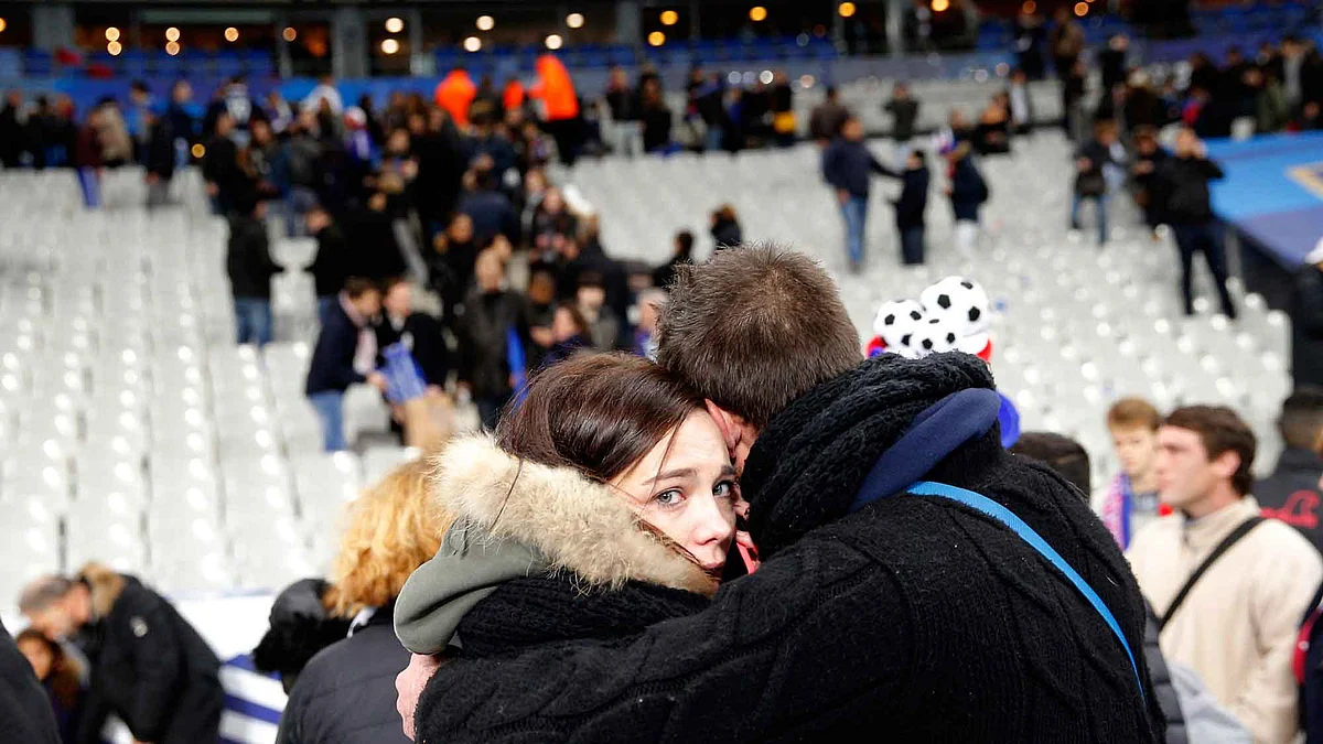 Spectators embrace each other as they stand on the playing field of the Stade de France stadium at the end of a friendly soccer match between France and Germany. (Photo: AP)