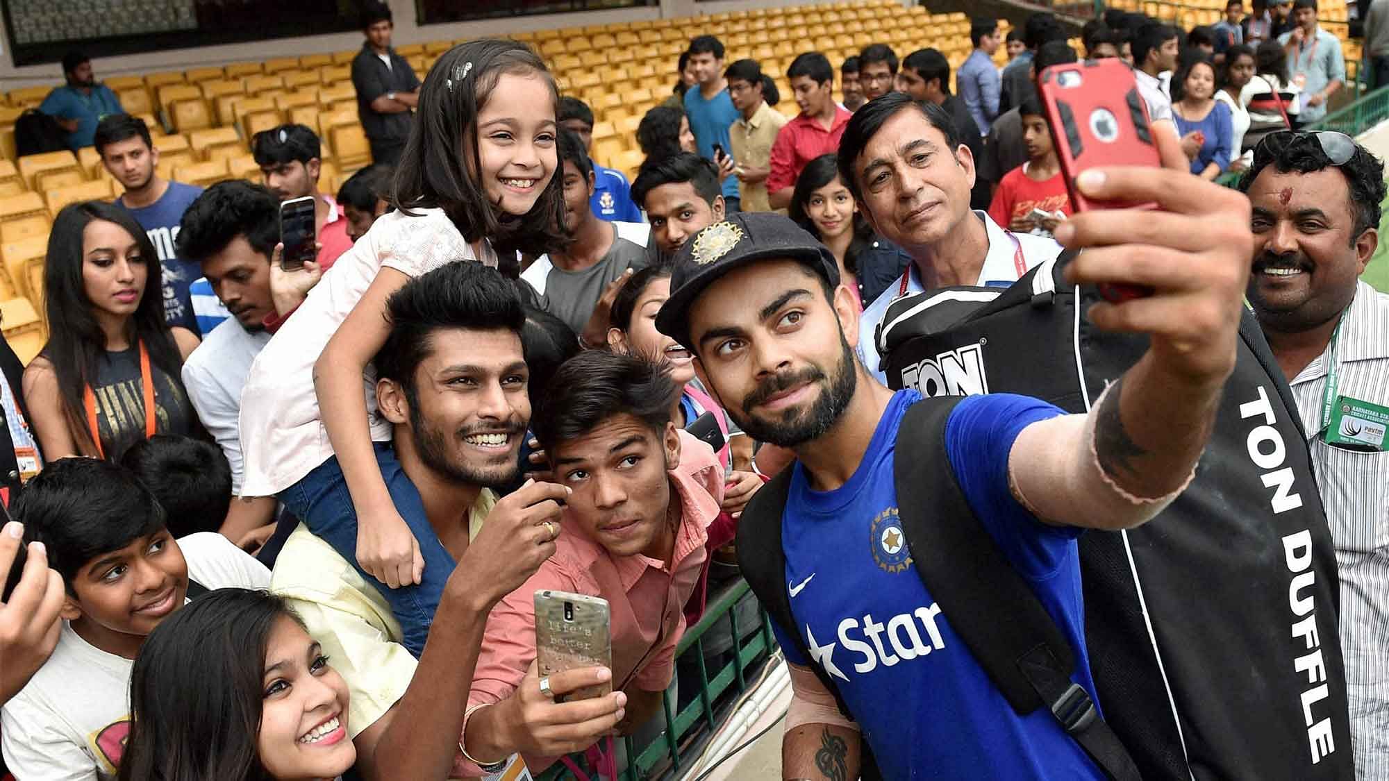 Indian Test skipper Virat Kohli takes pictures with fans before the Team’s practise session in Bangalore on Thursday. (Photo: PTI)