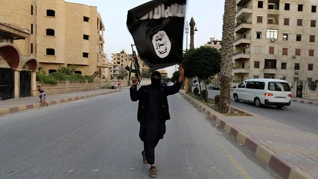 A member of the Islamic State waves an ISIS flag in Raqqa, Syria. (Photo: Reuters)