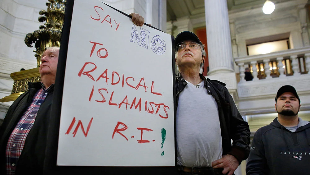 A protestor displays a placard during a rally, November 19, 2015, held to demonstrate against allowing Syrian refugees to enter Rhode Island following the terror attacks in Paris. (Photo: AP)
