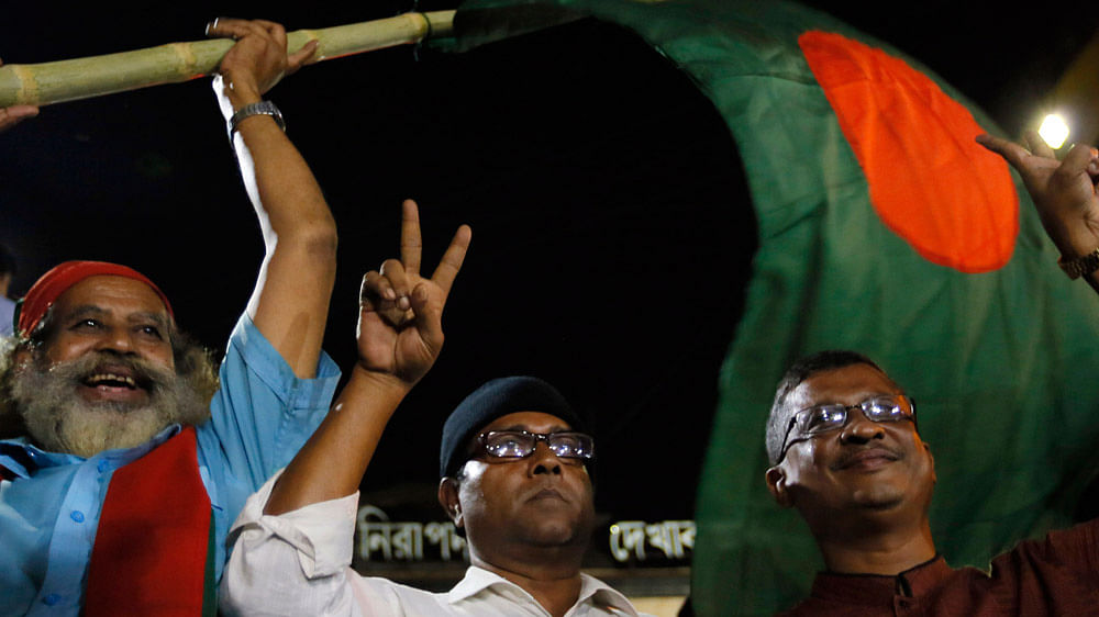 In this November 21, 2015 photo, a Bangladeshi activist waves the national flag as he celebrates outside the Central Jail, where two war criminals were executed in Dhaka, Bangladesh. (Photo: AP)