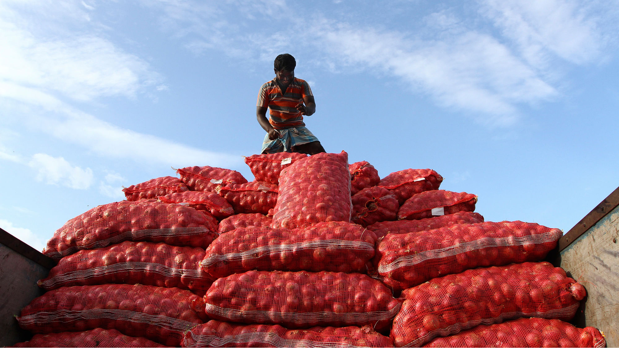 A labourer unloads sacks of onions from a supply truck at a vegetable wholesale market. (Photo: Reuters)&nbsp;