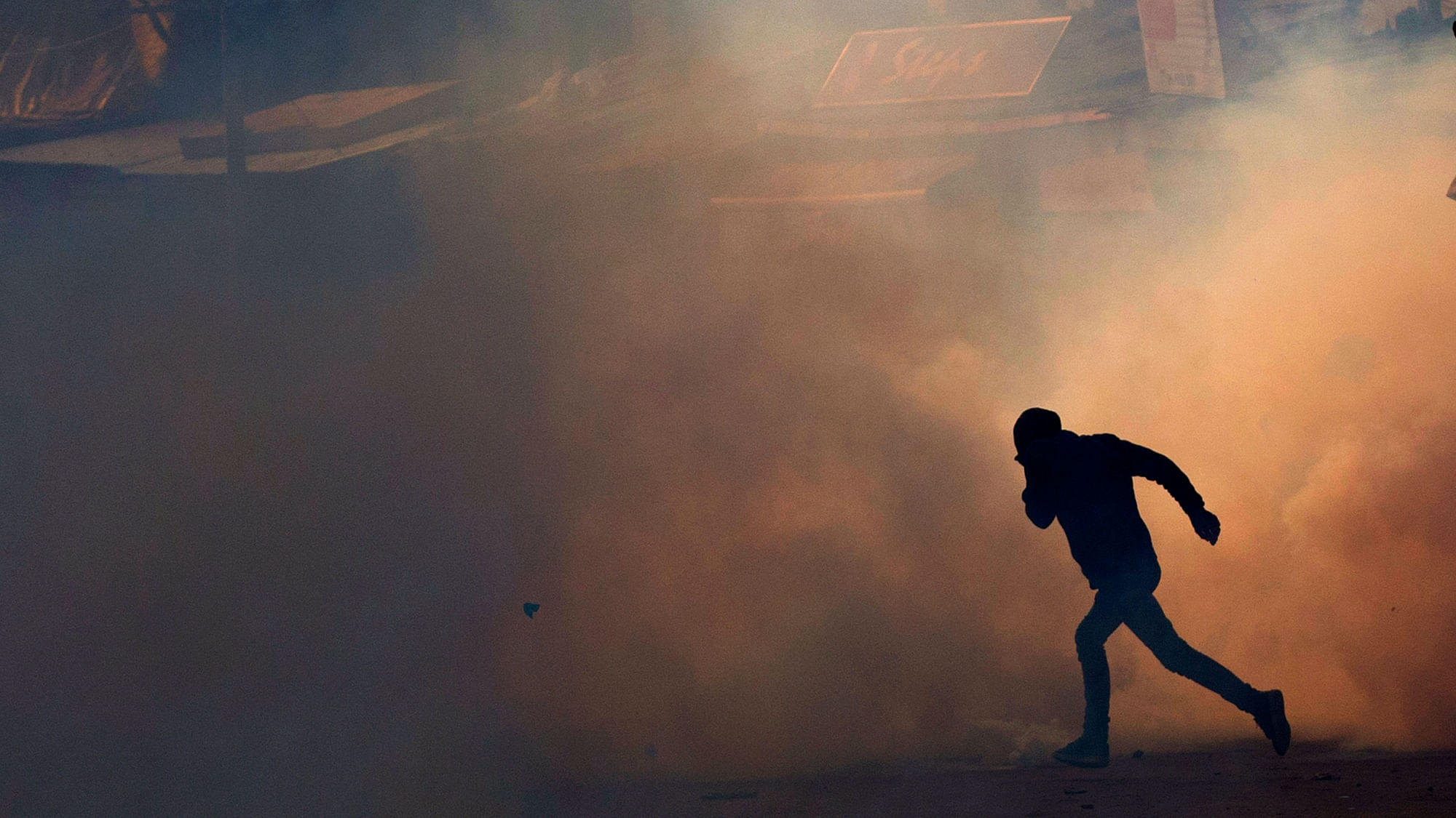 A Kashmiri protester runs for cover amid teargas smoke during a protest in Srinagar,  Kashmir.  (Photo: AP Photo/ Yasin Dar)