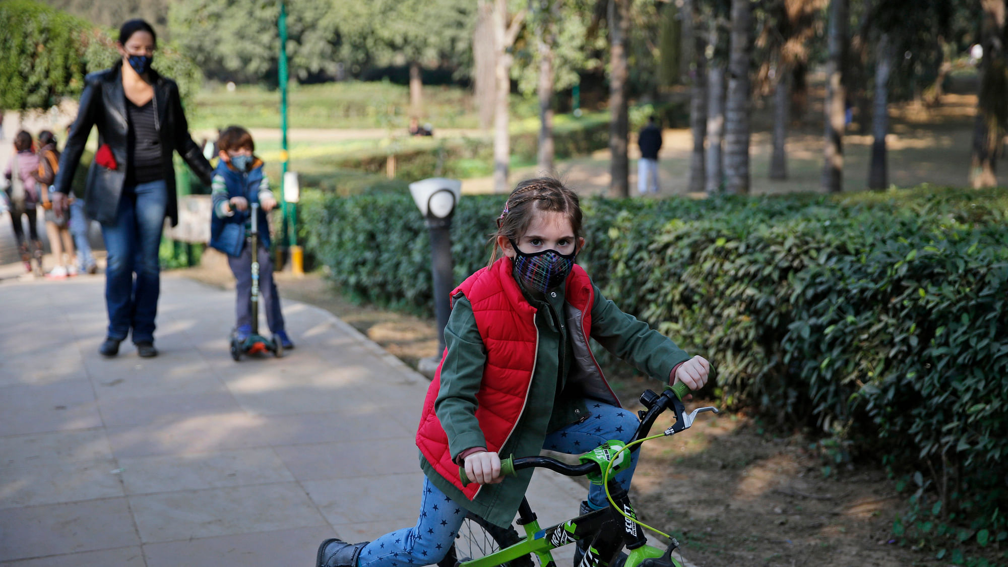 A girl rides a bicycle wearing a mask as she arrives for a picnic organised to promote awareness on severe air pollution in New Delhi. (Photo: AP) 