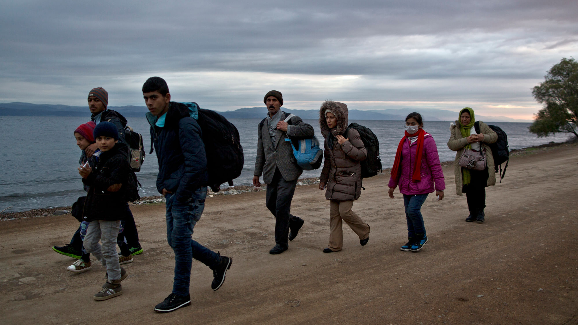 A Yazidi refugee family walk toward a gathering point to board a bus to a registration centre, after arriving on a vessel from the Turkish coast to the northeastern Greek island of Lesbos. (Photo: AP)