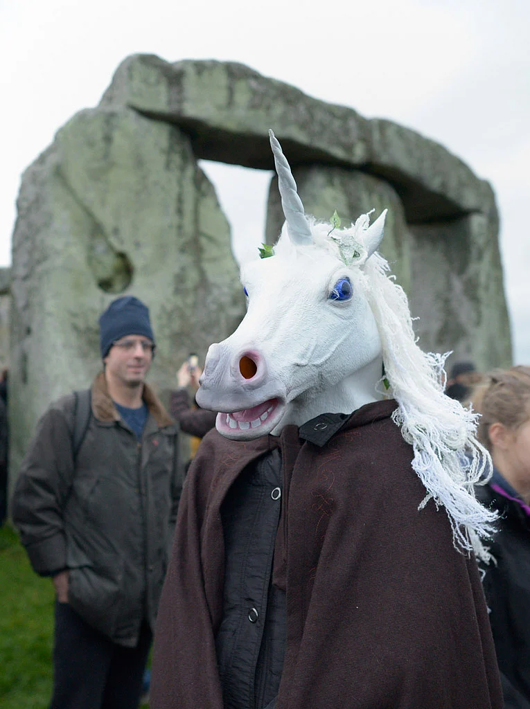 A person wearing a unicorn head joins others as people gather to celebrate the Winter Solstice at Stonehenge in England (Photo: AP)