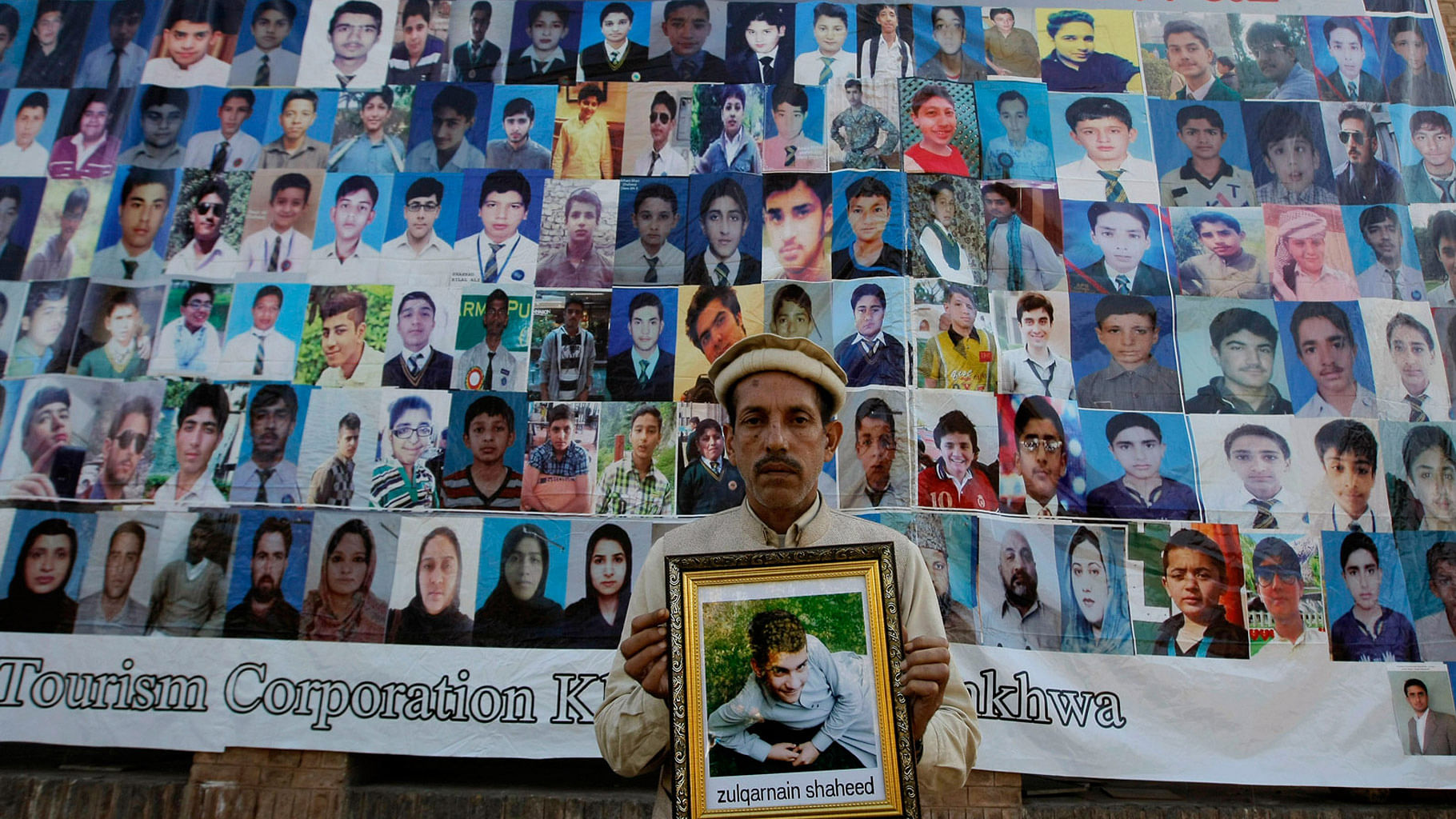 A Pakistani father holds a picture of his son who was killed in an attack, in front of photographs of other victims, ahead of the first anniversary of the Peshawar school attack on December 15. (Photo: AP)