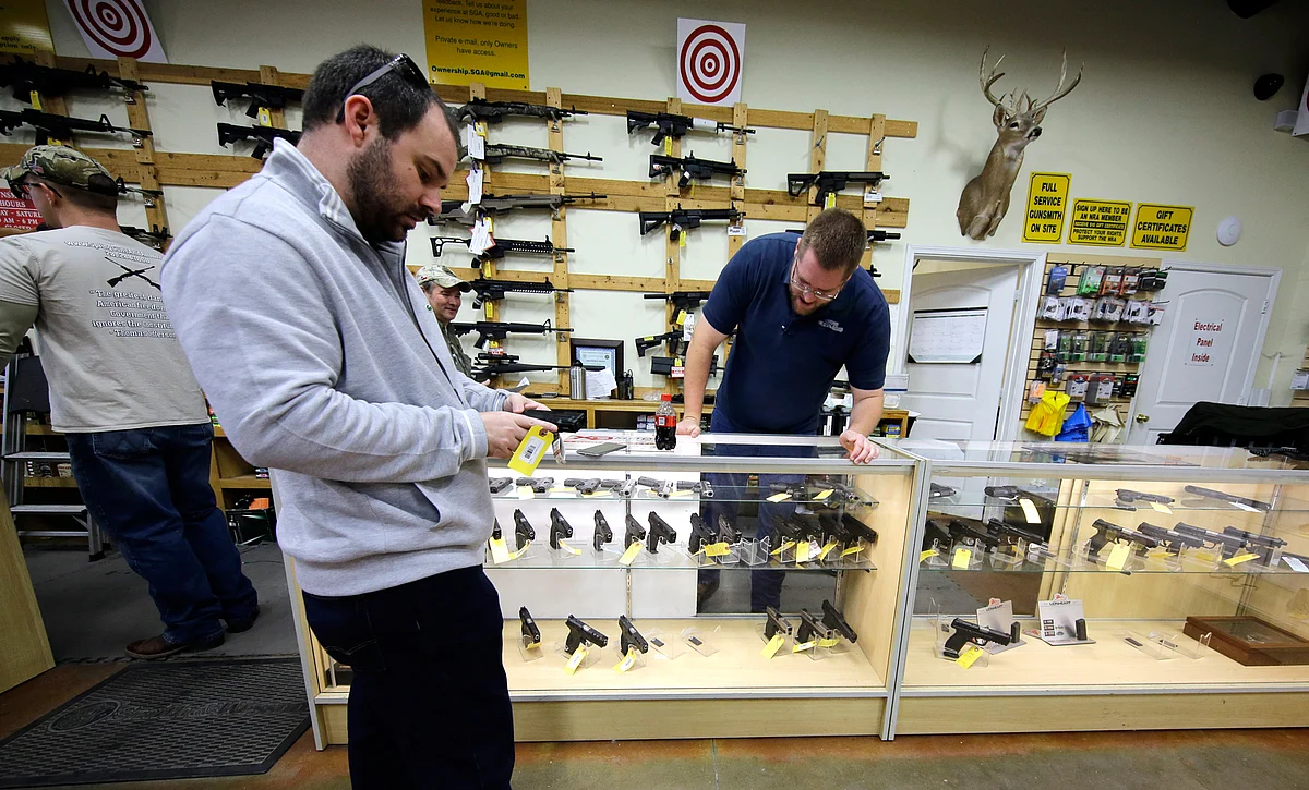 David Foley, center, looks as a handgun while shopping at the Spring Guns and Ammo store Monday, 4 January 2016, in Spring, Texas. (Photo: AP)