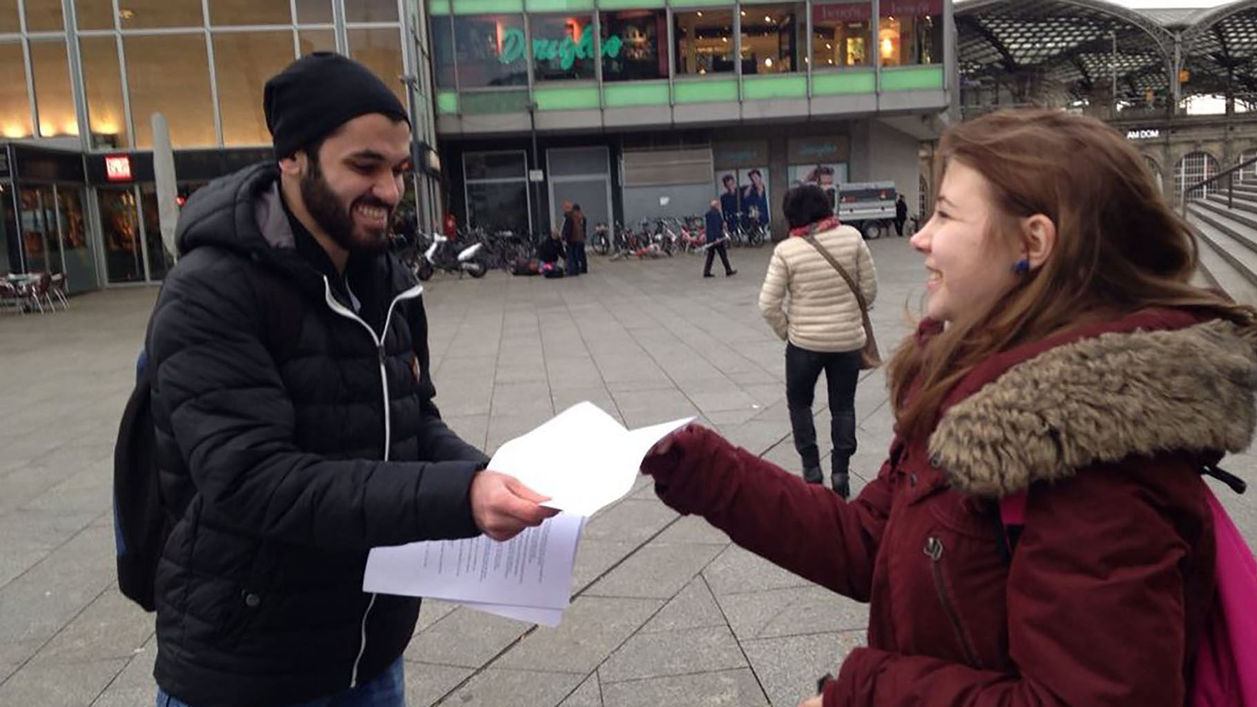 Syrian men handing leaflets to women in Cologne, condemning attacks on women on New Year’s Eve. (Photo courtesy: Twitter/<a href="https://twitter.com/lucyEgrey/status/687223849302245376">@lucyEgrey</a>)