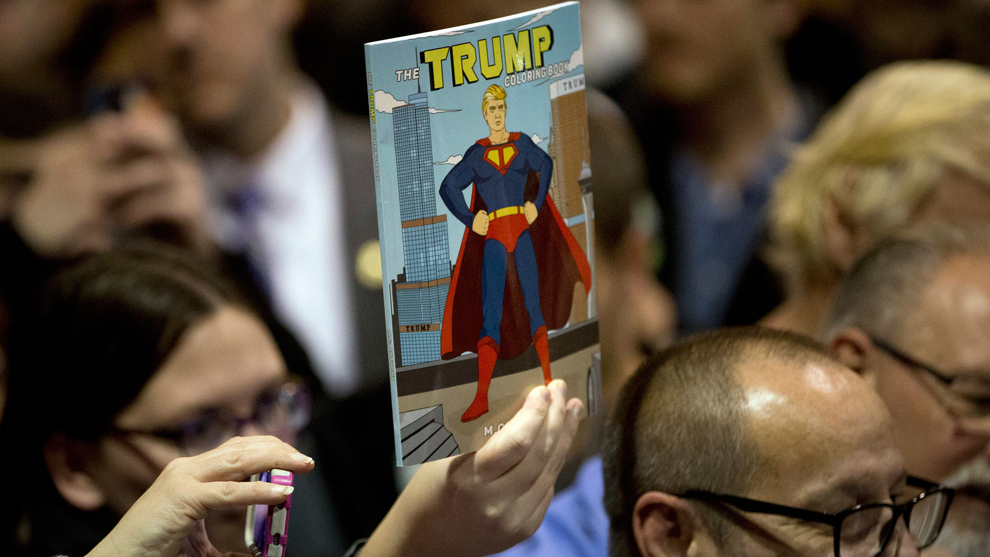 A woman holds up a Trump coloring book as Republican presidential candidate Donald Trump greets supporters after a rally. (Photo: AP)
