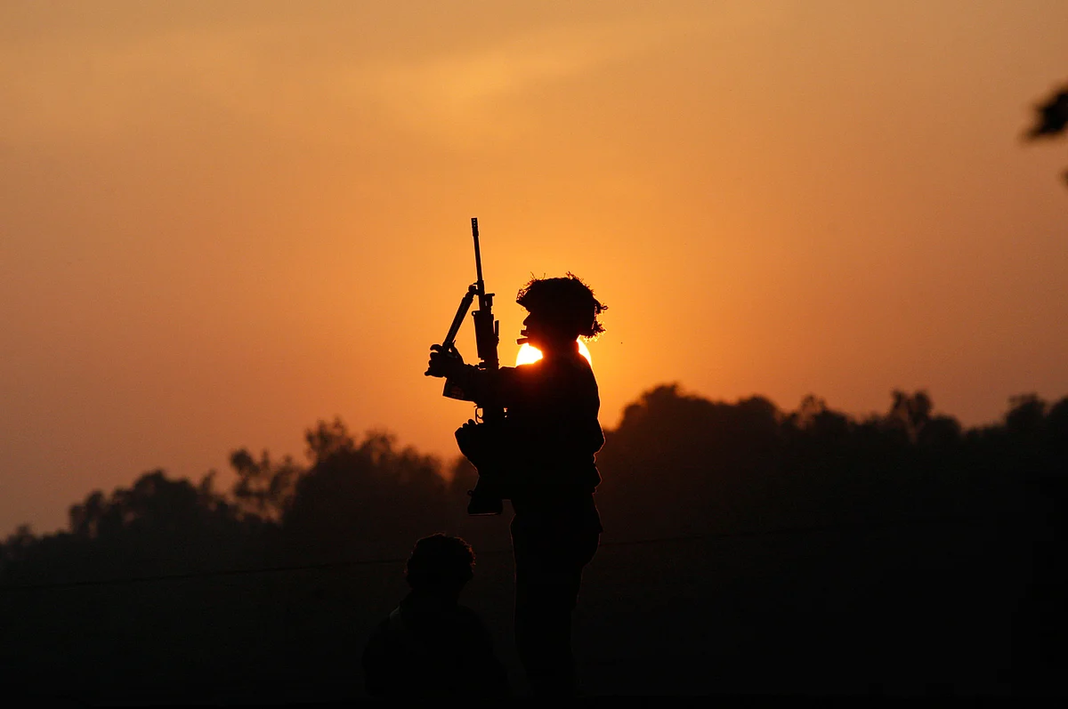 An Indian army soldier is silhouetted against the setting sun as he stands guard next to his colleague, sitting on the roof top of a house outside the Indian air force base in Pathankot, India. (Photo: AP) 
