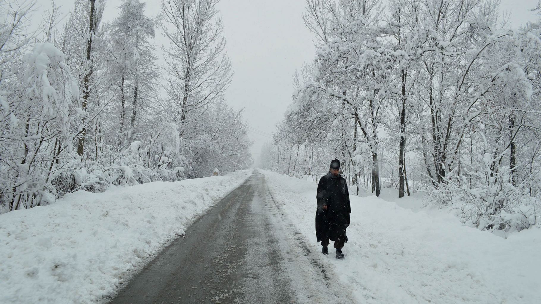 A Kashmiri man walks through a snow-covered road in Anantanag. (Photo: IANS)&nbsp;
