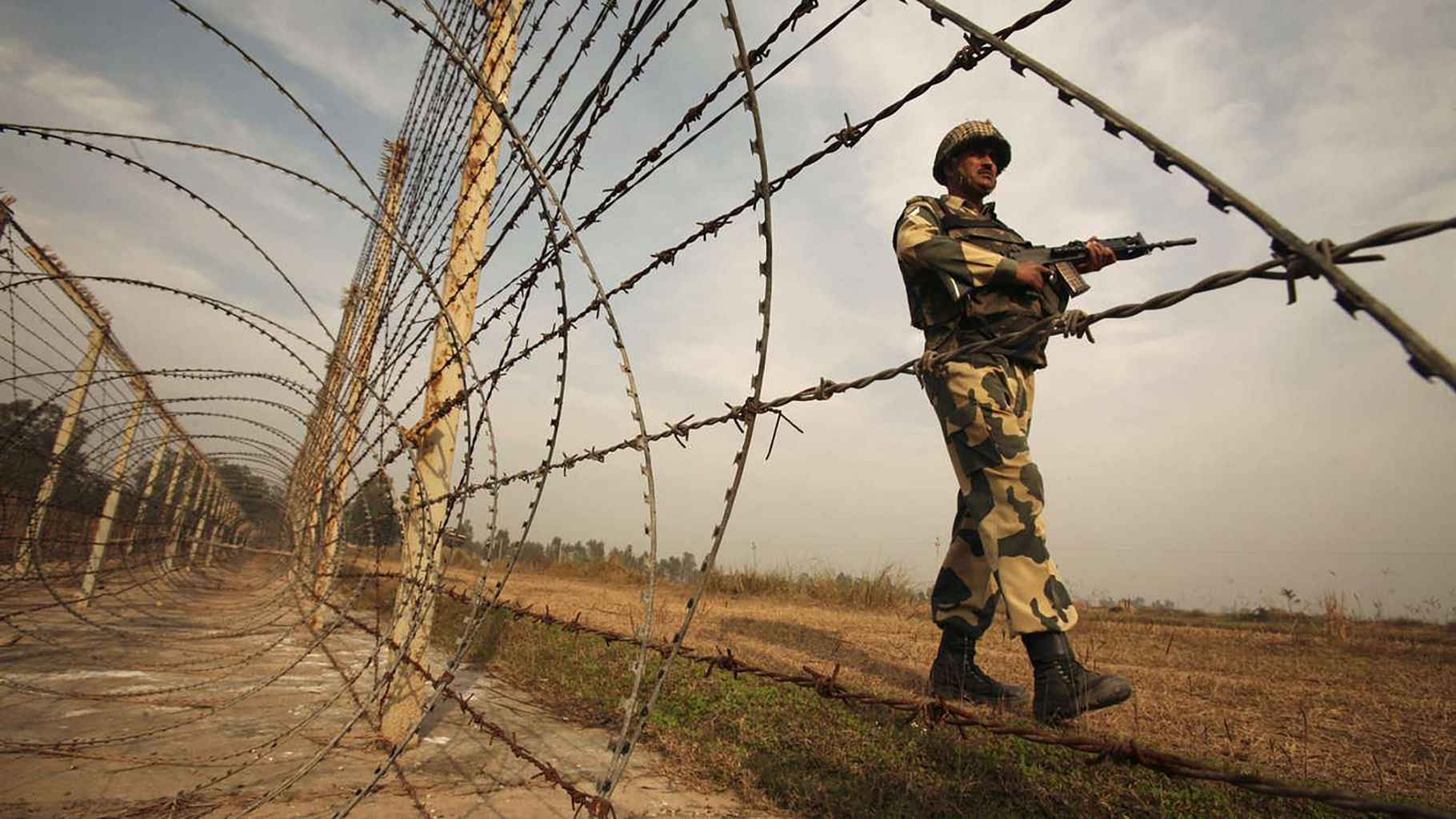 An Indian Border Security Force soldier patrols the fenced border with Pakistan. (Photo: Reuters)