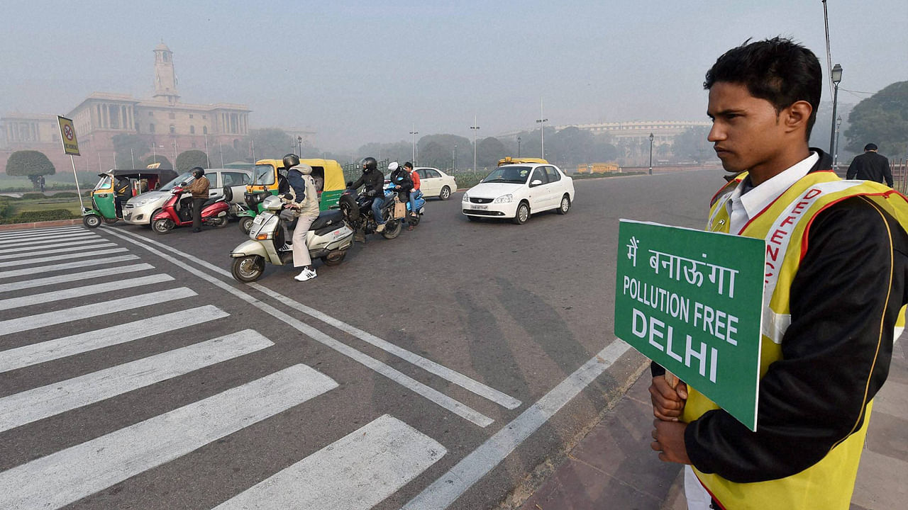 A Civil Defence volunteer holding a placard at Vijay Chowk as the odd-even scheme restricts the movement of private cars in New Delhi on Monday. (Photo: PTI)&nbsp;