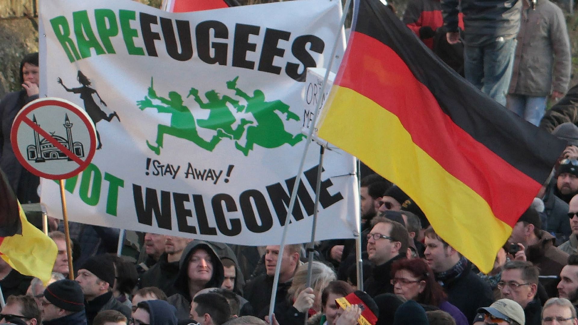 Right-wing demonstrators hold a sign saying “Rapefugees not welcome - !Stay away!” and a sign with a crossed out mosque as they march in Cologne, Germany. (Photo: AP)