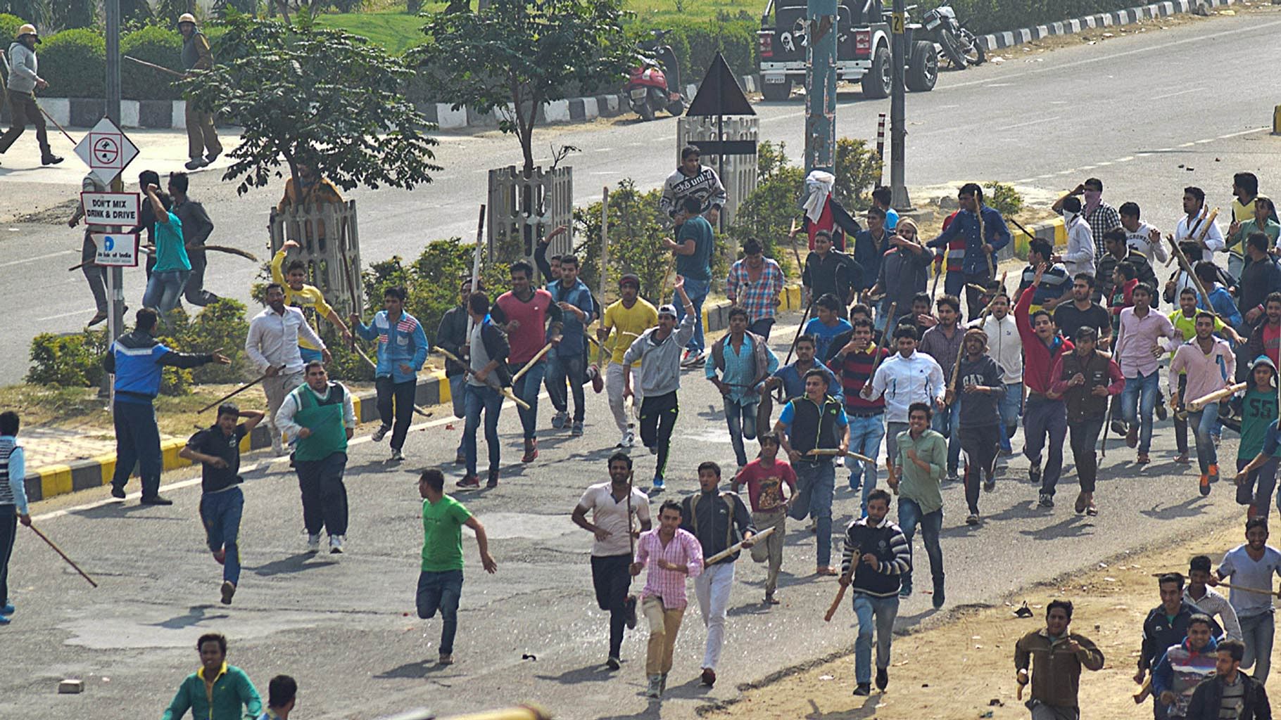  Protestors run  with sticks during a pro-caste quota protest in Rohtak. (Photo: AP)