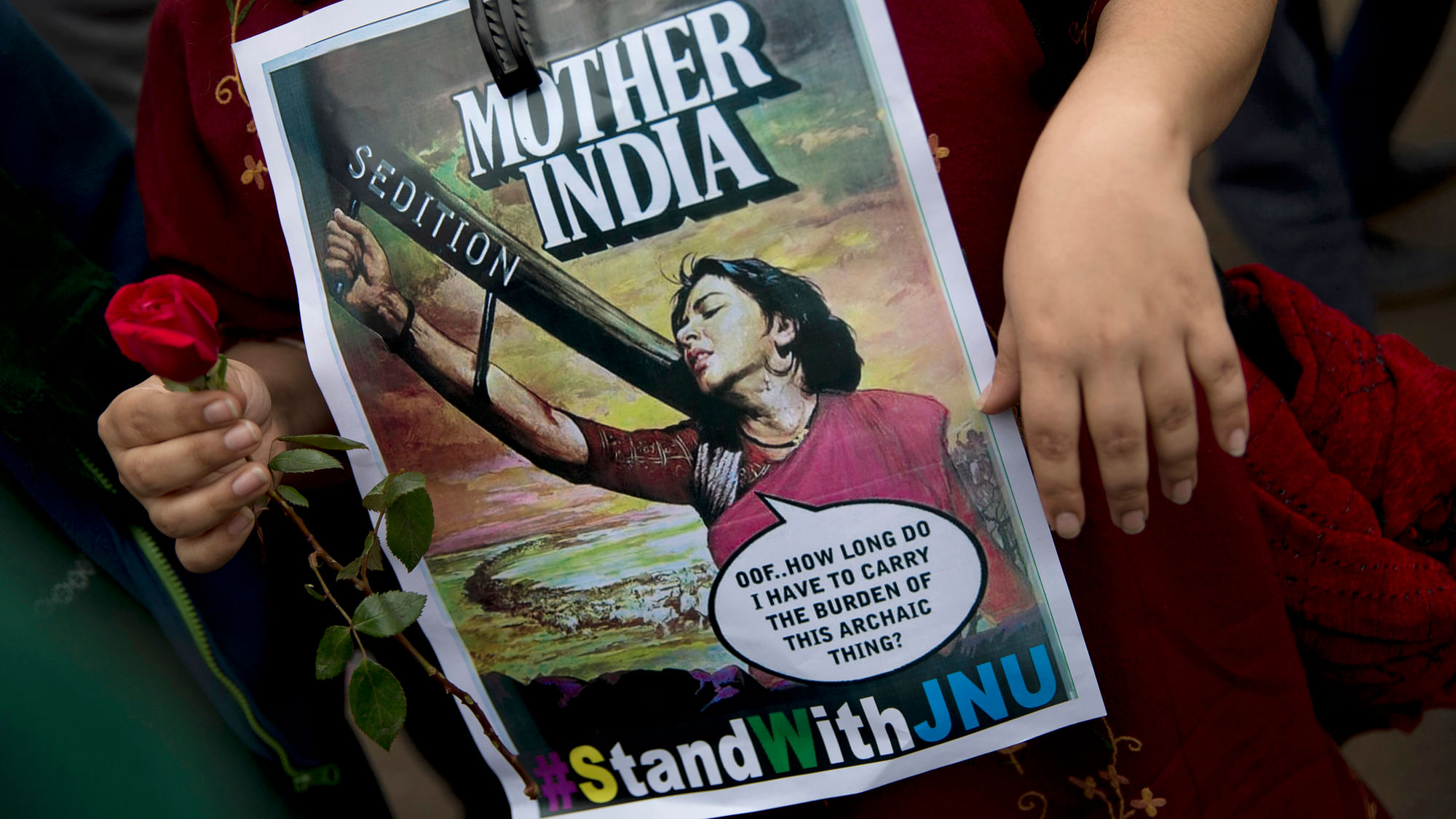 A student carries a flower and holds a poster during a rally at the JNU, protesting Kanhaiya Kumar’s arrest. (Photo: AP)