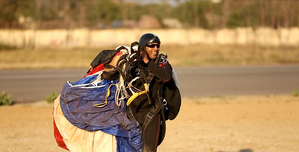 Tandem master, Rajkumar, gathers his parachute after landing. (Photo: <b>The Quint</b>)