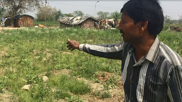 Farmer Indradev Sharma points out at the boulders scattered through his field. (Photo: The Quint)