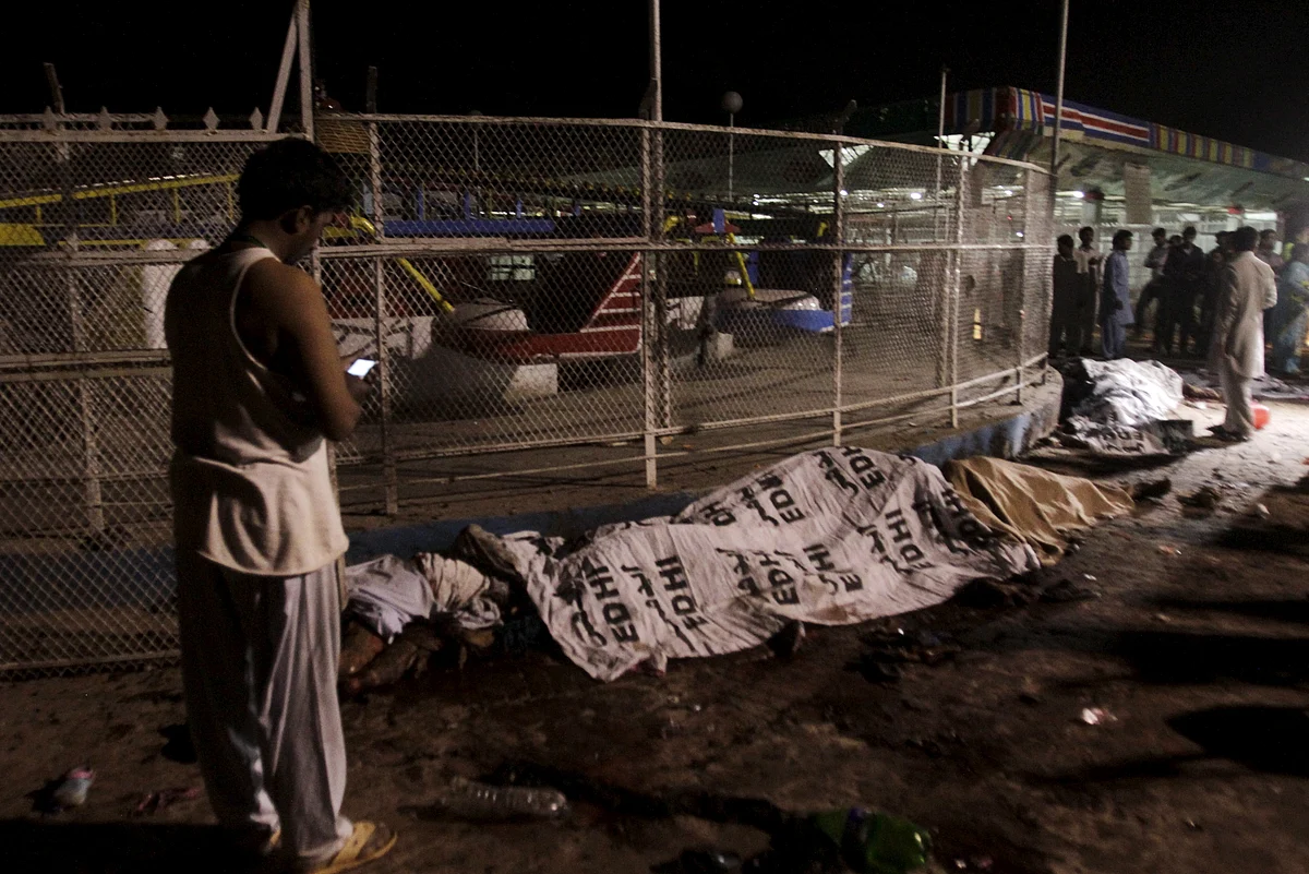 A man stands next to bodies covered in sheets at the site of a blast, outside a public park in Lahore. (Photo: Reuters/Mohsin Raza)