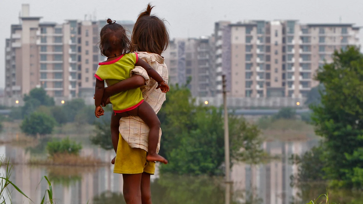 A girl carrying a child stands outside her makeshift tent in front of the athletes village of the 2010 Commonwealth Games, while surrounded by flood waters of the river Yamuna. (Photo: Reuters)