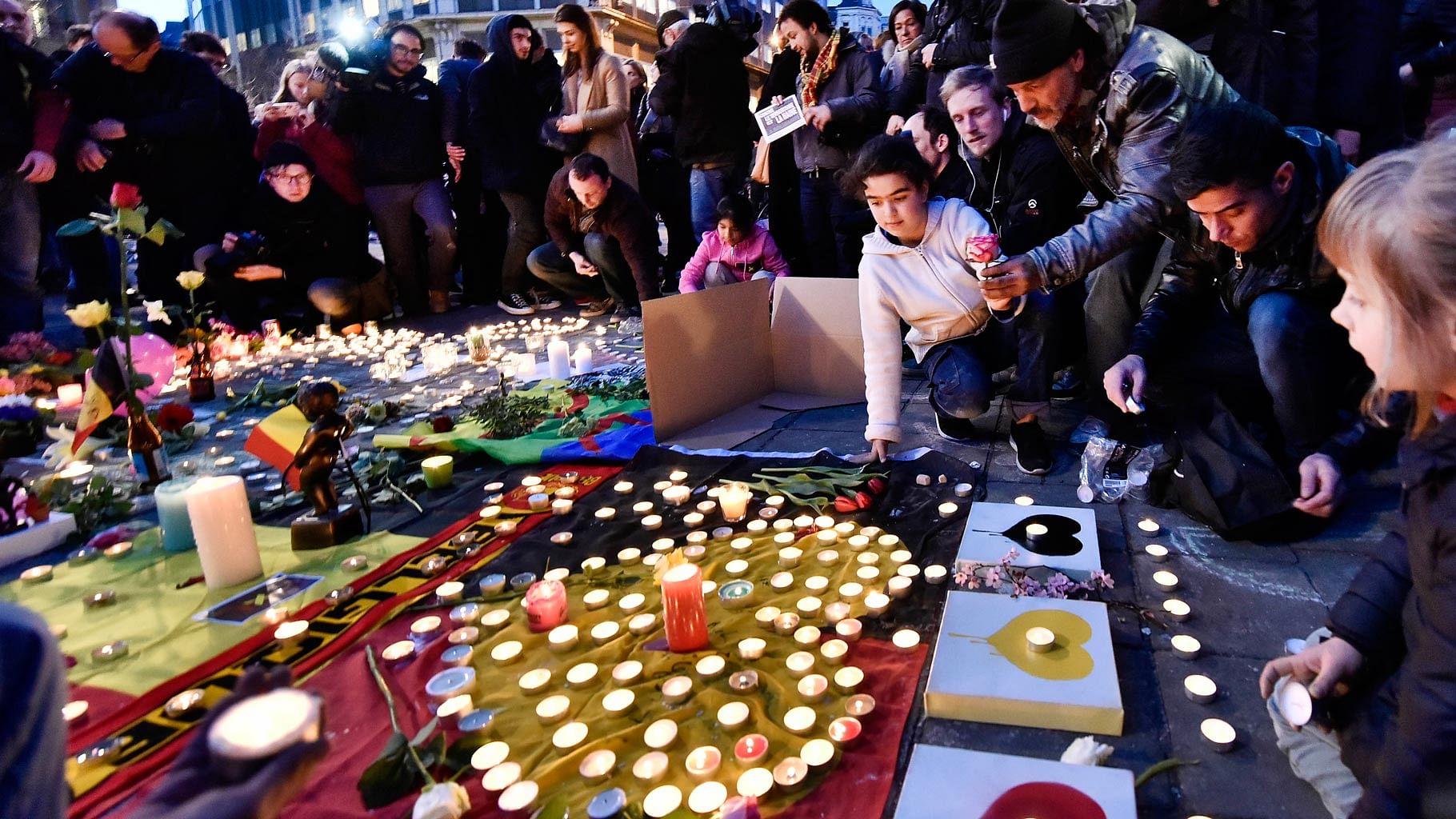 People bring flowers and candles to mourn for the victims at Place de la Bourse in the center of Brussels, Tuesday, March 22, 2016. 
