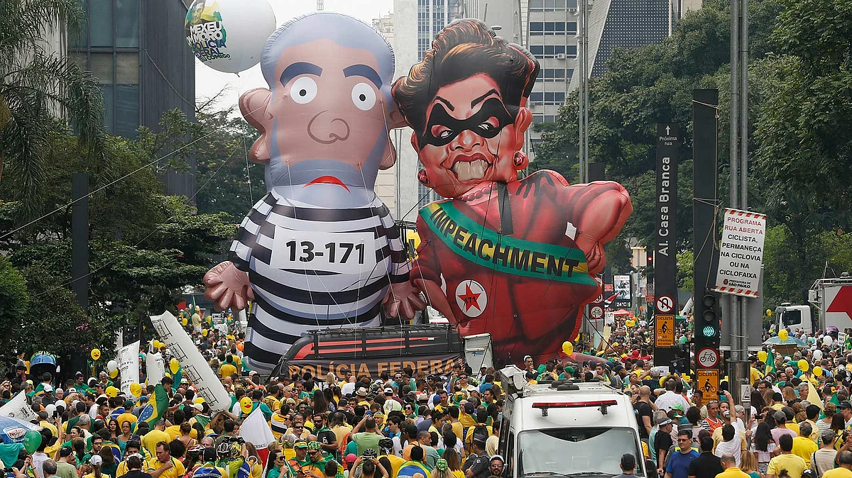 Demonstrators parade large inflatable dolls depicting Brazil’s former President Luiz Inacio Lula da Silva in prison garb and current President Dilma Rousseff dressed as a thief, with a presidential sash that reads “Impeachment,” in Sao Paulo, Brazil, 13 March 2016. (Photo: AP)