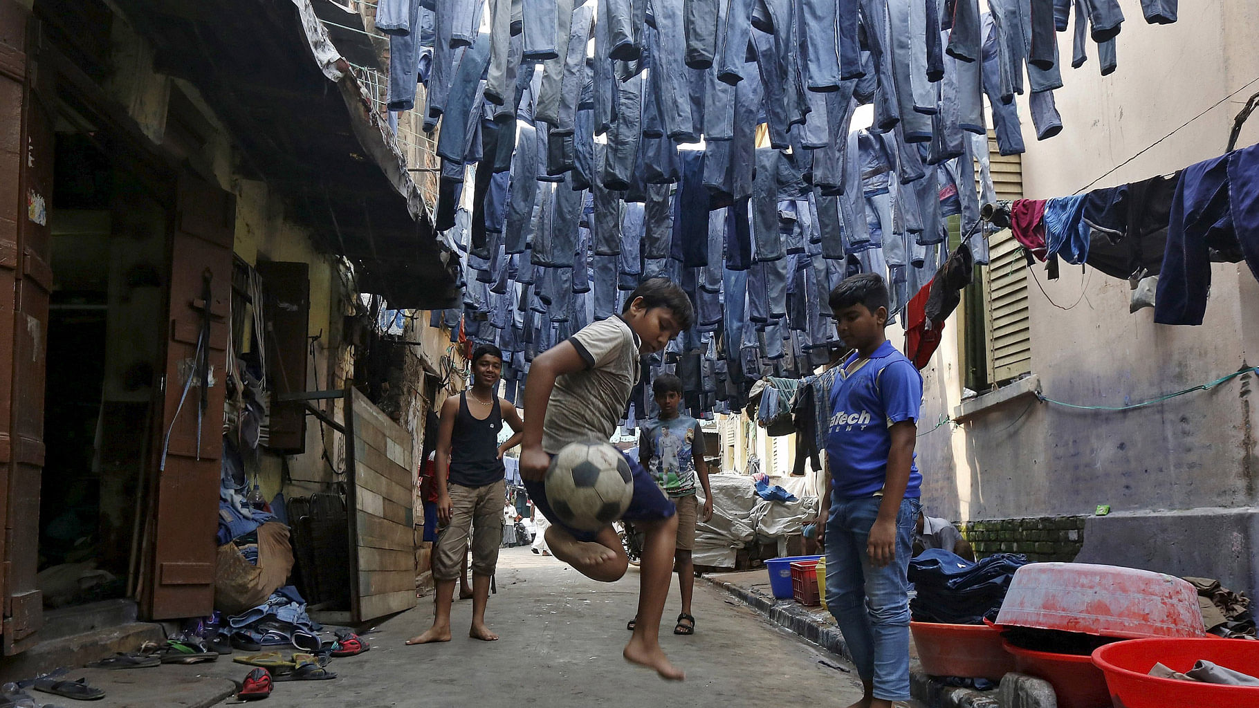 

Mohammad Afroze, 15, playing  soccer in an alley as used pairs of jeans  hang  to dry before they are sold in a second-hand clothes market in Kolkata, India, March 10, 2016.  (Photo: Reuters)