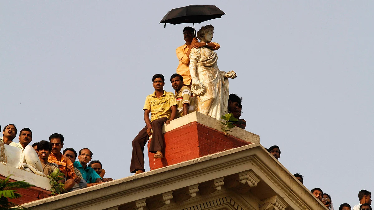 People stand atop Writers’ Building to get a glimpse of TMC chief Mamata Banerjee after she took oath as the chief minister, in Kolkata May 20, 2011. (Photo: Reuters)