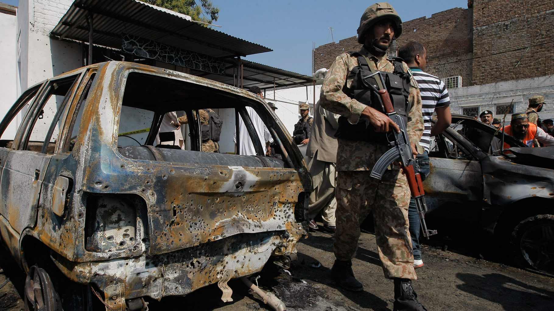 A Pakistani soldier  walks past damaged vehicles at the site of a deadly suicide bombing in Charsadda. (Photo: AP)