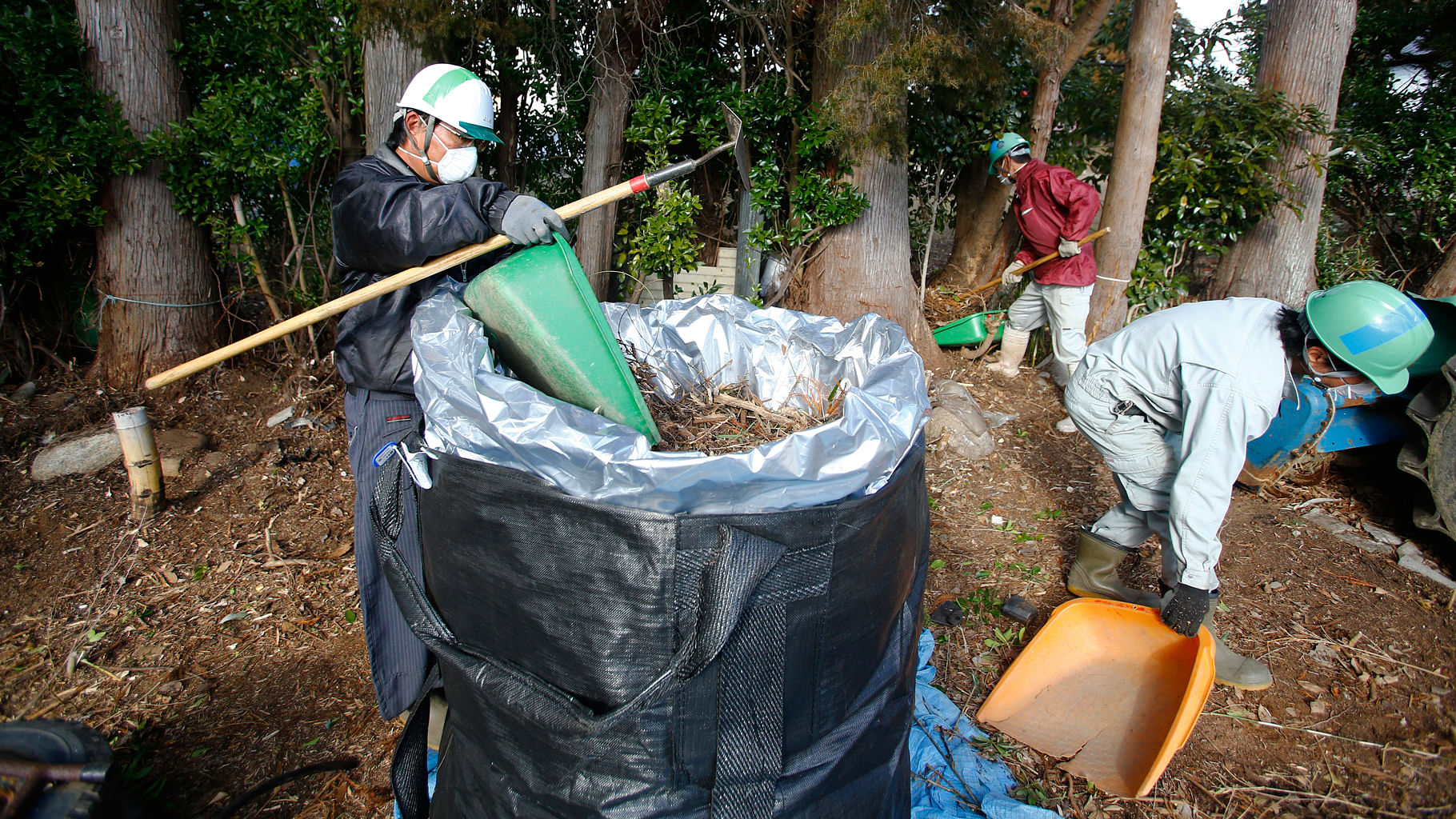 Workers clean radioactive soil and plants in a private home in Minamisoma, Fukushima Prefecture. (Photo: AP)